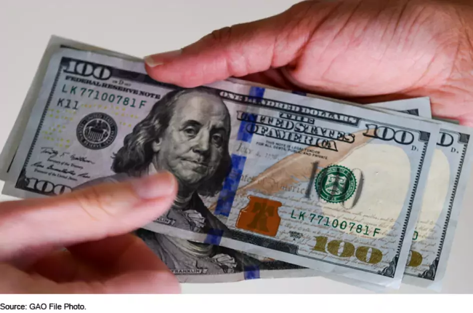 Photo showing two hands exchanging money ($100 bills).