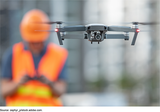 An image of a person wearing a safety vest operating a drone.