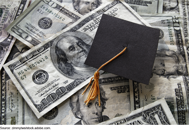 Photo showing large U.S. dollar currency ($100s, $20s, and $1s) with a graduation cap laying on top.