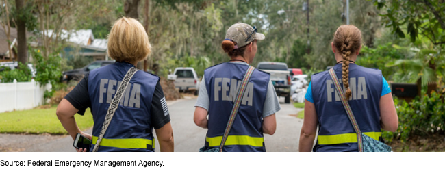Three people in FEMA vests walking in a residential area