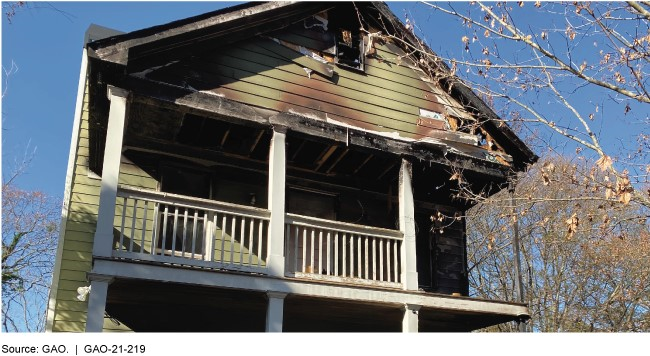 The exterior of a house with a damaged upper-level porch and roof.