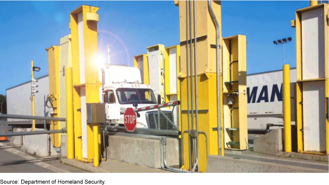 Semi-trucks being scanned by large detection devices at a checkpoint
