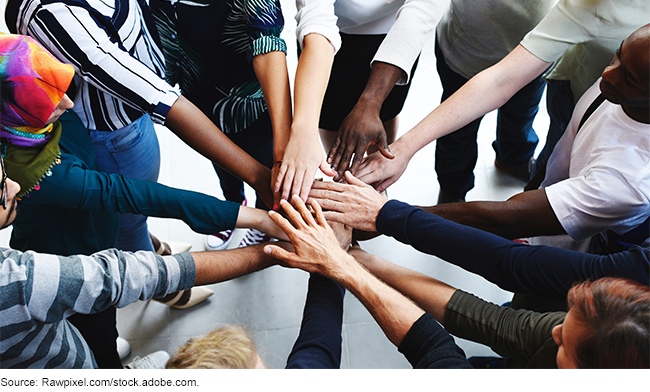A group of people placing hands in the middle of a circle.