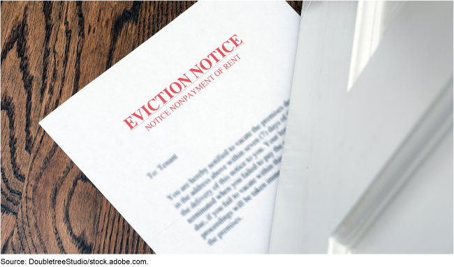 A paper eviction notice being slipped beneath a door.