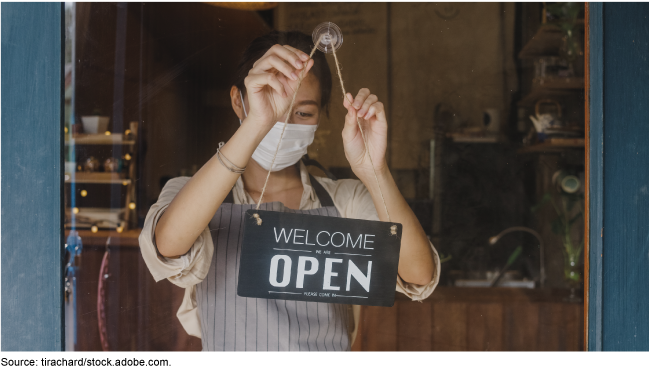 A woman hanging an open sign for her business