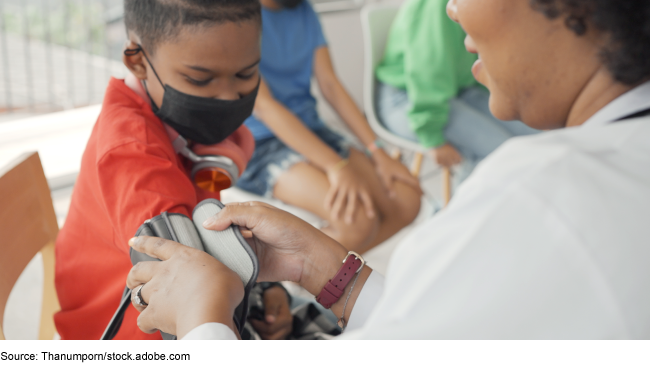 Photo of a nurse putting a blood pressure cuff on a child's arm