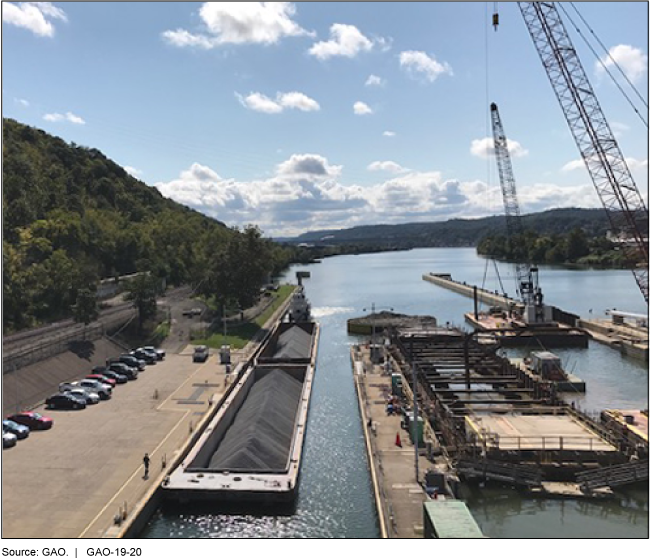 This is a photo showing a towboat bringing two barges through a lock and a new lock under construction. 