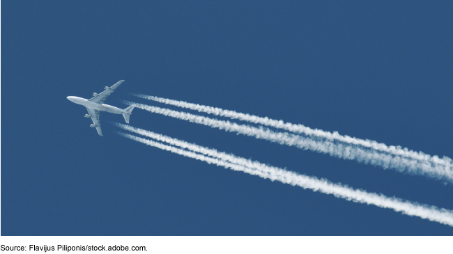 An airplane flying in the sky with plane trails.