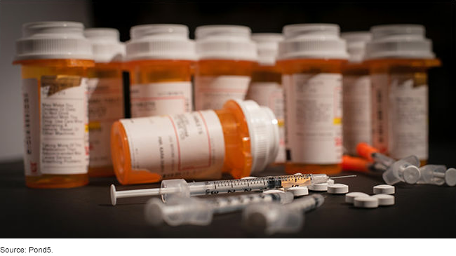 An image of prescription containers and drug syringes. 