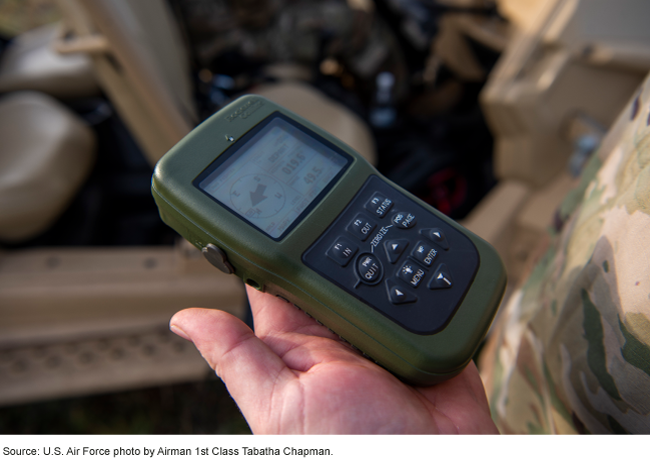 person in military uniform holding a handheld GPS receiver