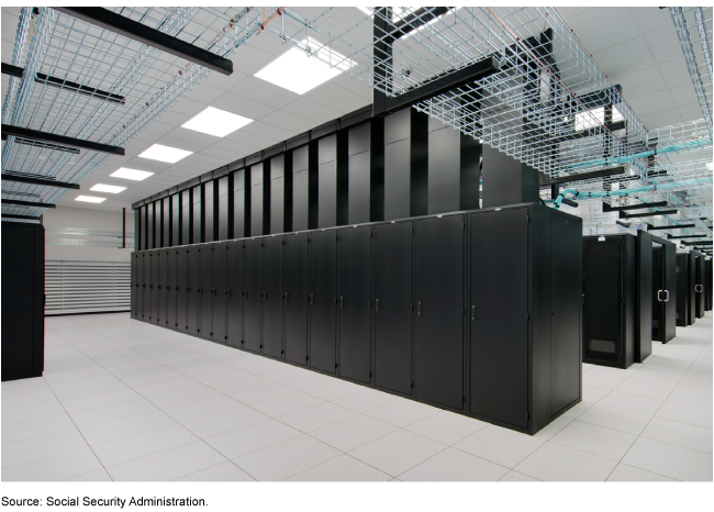 Large black data servers in a line on a white-tiled floor.