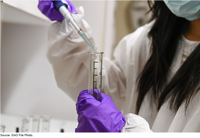 A person working in a lab and wearing a lab coat and safety equipment