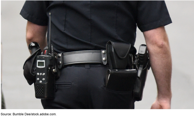 Close up of the back and waist of a police officer in uniform wearing a police duty belt.