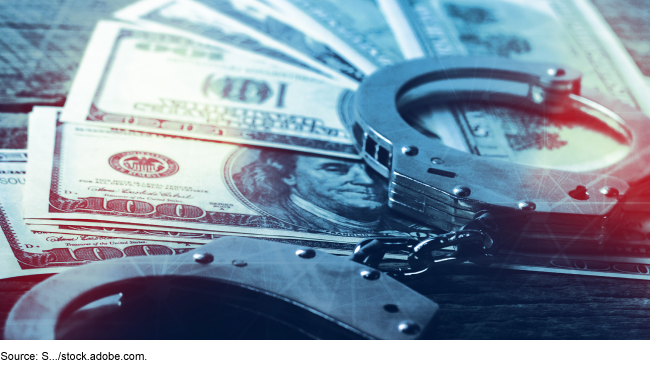 Handcuffs sitting on a pile of 100-dollar bills