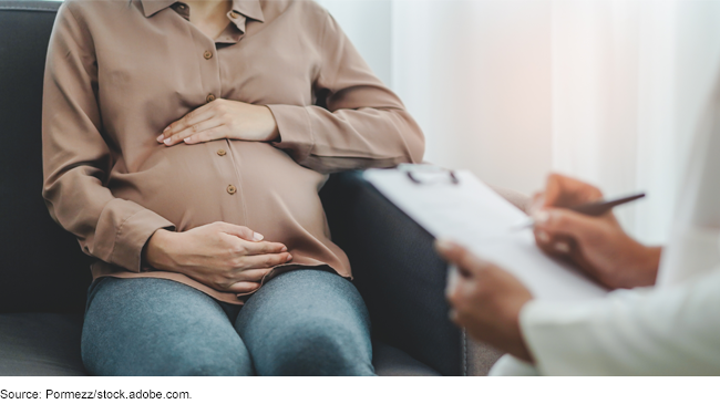 A pregnant person sitting across from a medical worker with a clipboard
