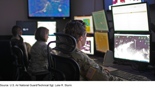 3 people in military fatigues working at computers