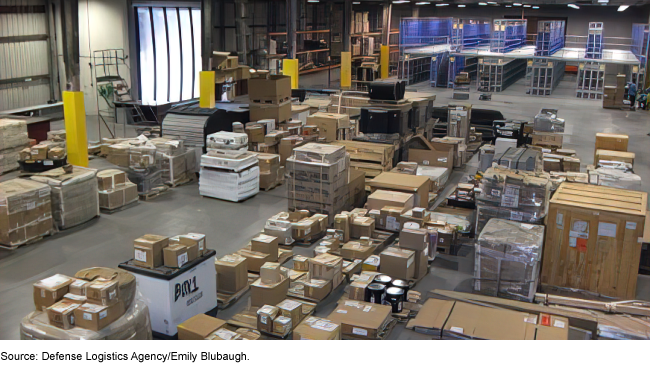 A photo inside a warehouse: a massive concrete and metal room with items stored on pallets, and in boxes, crates, and cartons