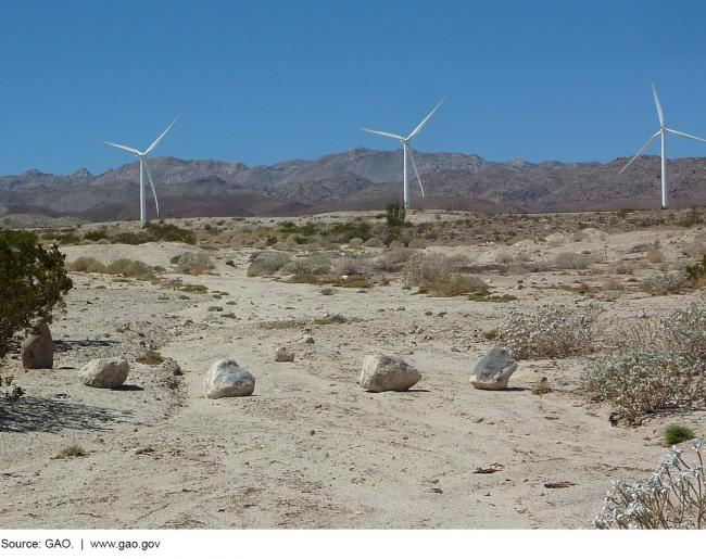 Wind turbines on a dry landscape with mountains in the background 