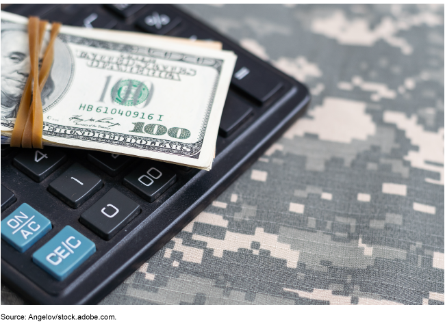 A calculator and U.S. money on top of a U.S. military uniform.