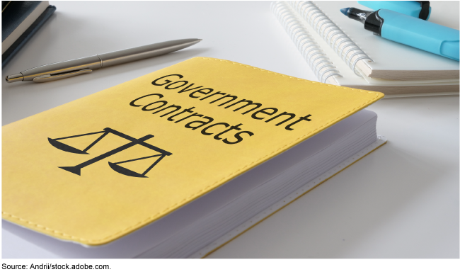A yellow book with cover text: Government Contracts, sitting on a desk with notebooks, a pen and highlighters around it. 