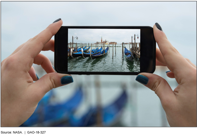 Photo of a person holding up a cell phone to take a photo of boats.