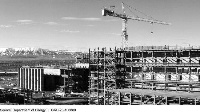 A building under construction, a crane, and mountains in the background