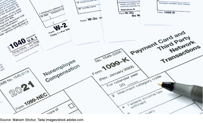 Various IRS forms spread out, with an ink pen resting on them. 