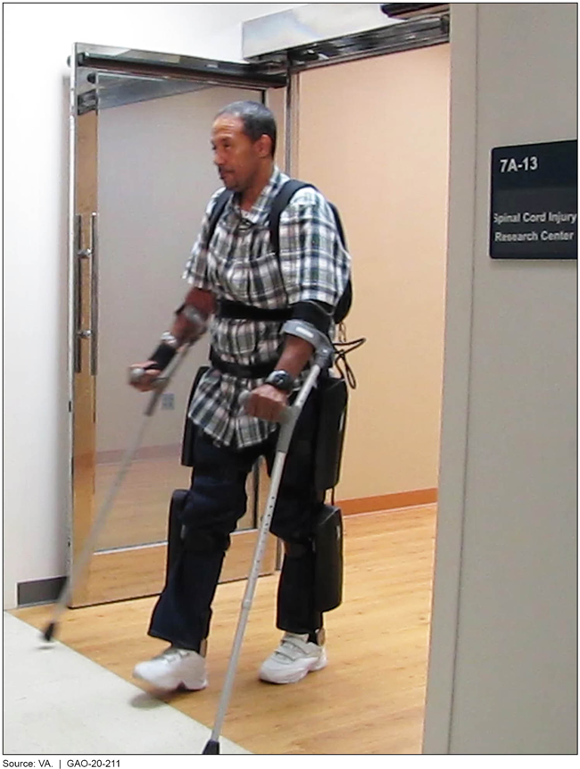 A man using an exoskeleton to walk out of a spinal cord injury research center