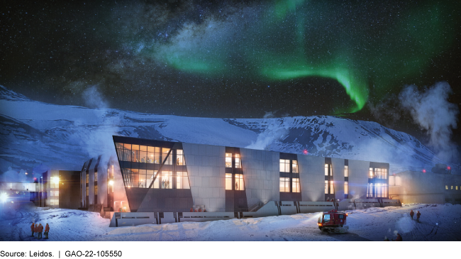 Green aurora in the night sky above a building surrounded by snow