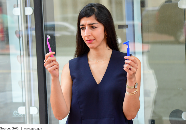 Photo of a woman holding a pink razor in one hand, and a blue one in another, and looking perplexed