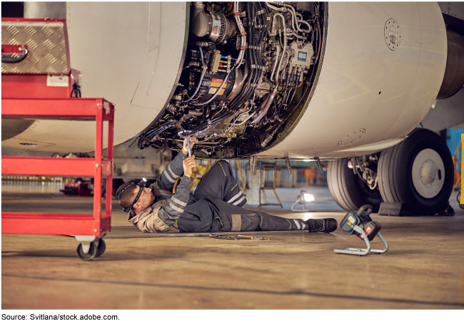 image of a mechanic laying on the floor working on a plane