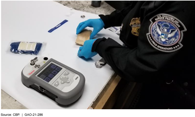 uniformed and gloved officer with a device and samples