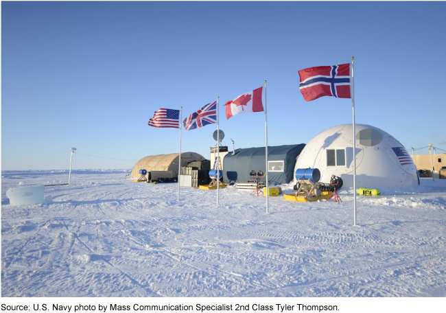 Three buildings behind 4 flags (U.S., U.K, Canada and Norway) on a snowy plane in the Artic. 