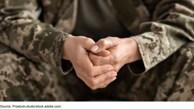 close up image of hands of person in a camouflage uniform
