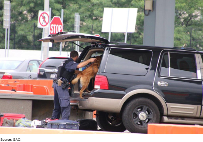An officer and a dog inspecting the trunk of an SUV