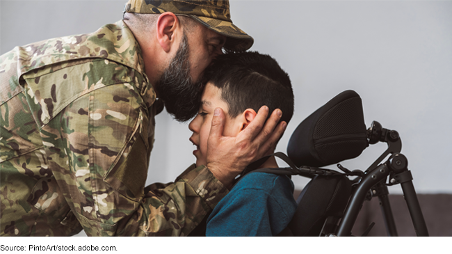 Servicemember in fatigues embracing a child who uses a wheelchair