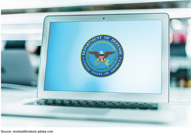 A laptop open on a desk with the Department of Defense logo on the screen.