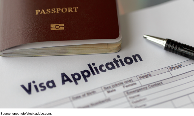 A VISA application with a passport and an ink pen sitting on top of it