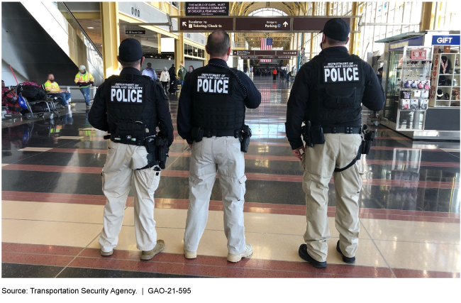 Three air marshals standing side by side in an airport terminal.