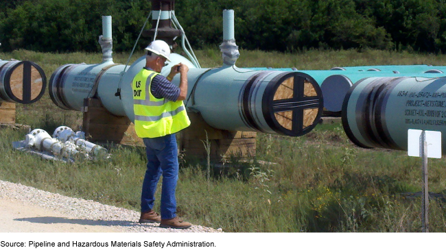 A worker in a safety vest examining a pipeline. 