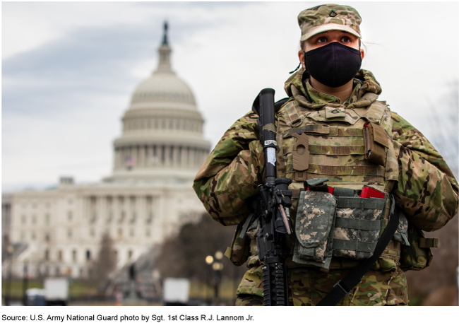 A service member stands guard outside in Washington, D.C. with the U.S. Capitol in the background.