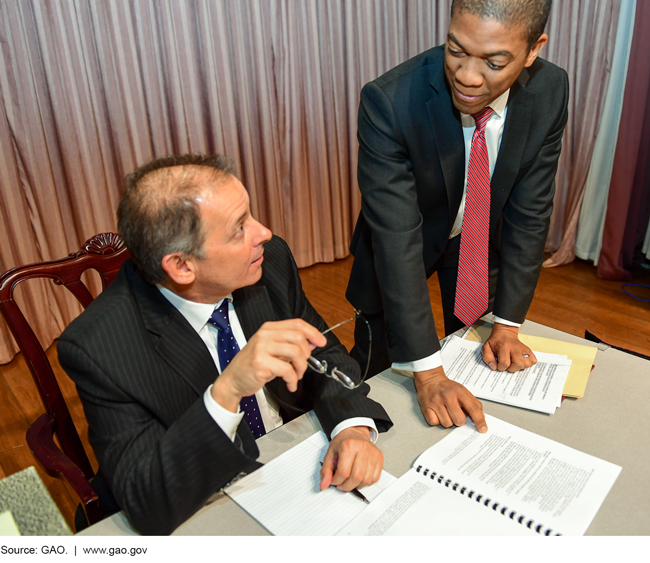 Photo of two men in suits looking over papers on a desk