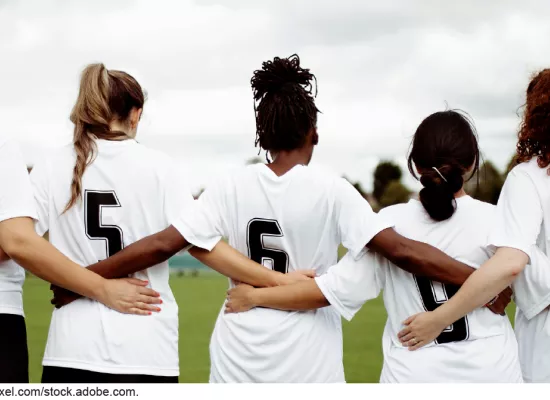 Stock image showing 5 women in soccer jerseys linking arms
