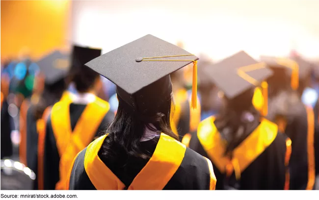 Stock image showing college graduates in cap and gown with gold sashes. 