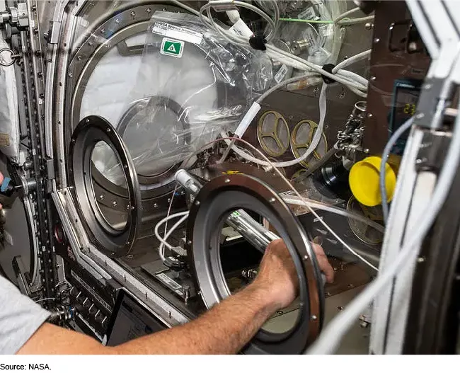 Photo showing a NASA Astronaut using a Microgravity Science Glovebox for Experiment