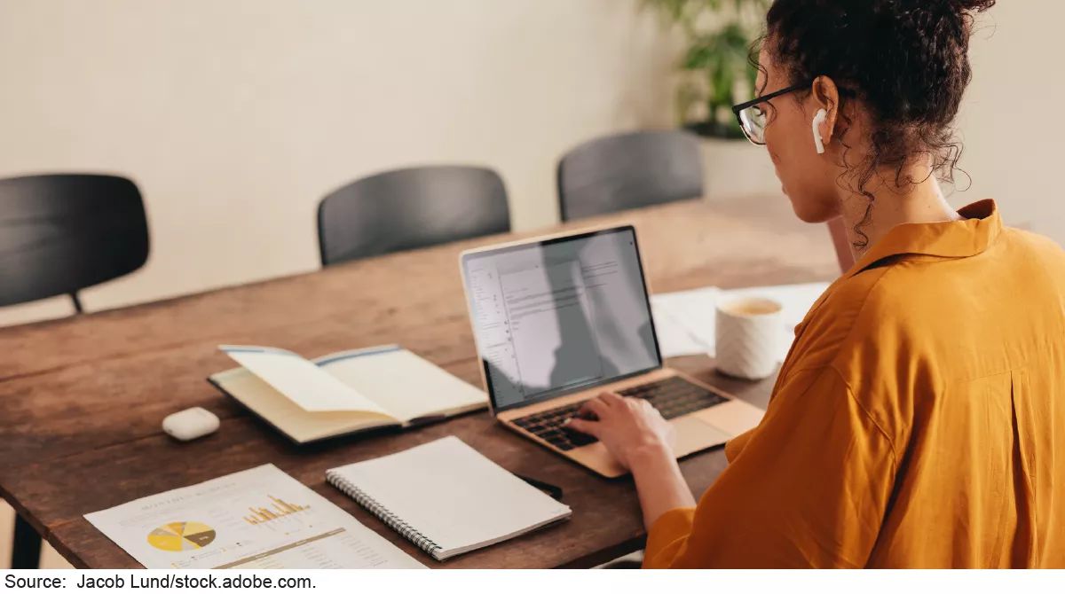 Image showing a woman working on a laptop from her diningroom table.