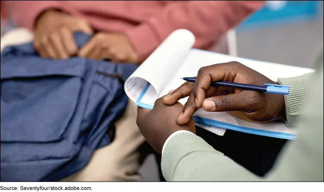 Stock image showing a mental health workers and a student sitting side by side in discussion.