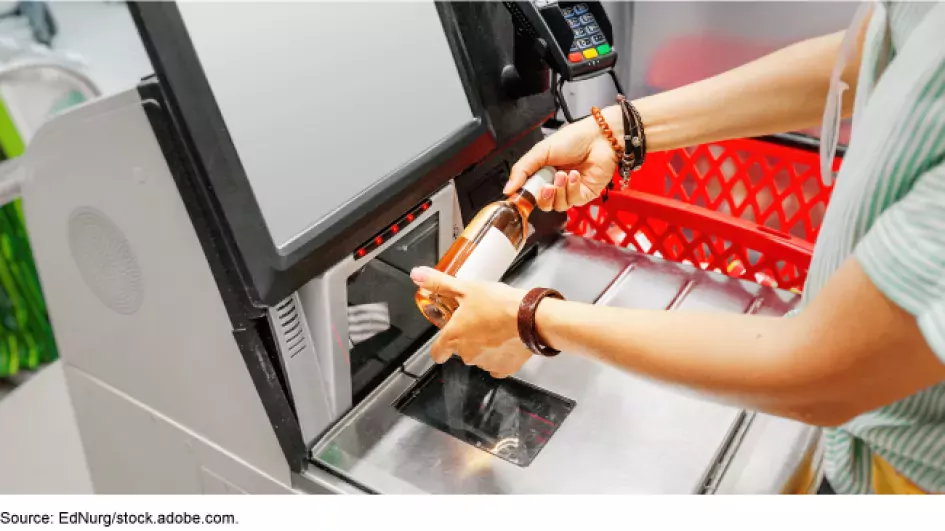 Photo of a woman using a self-check-out machine in a grocery store