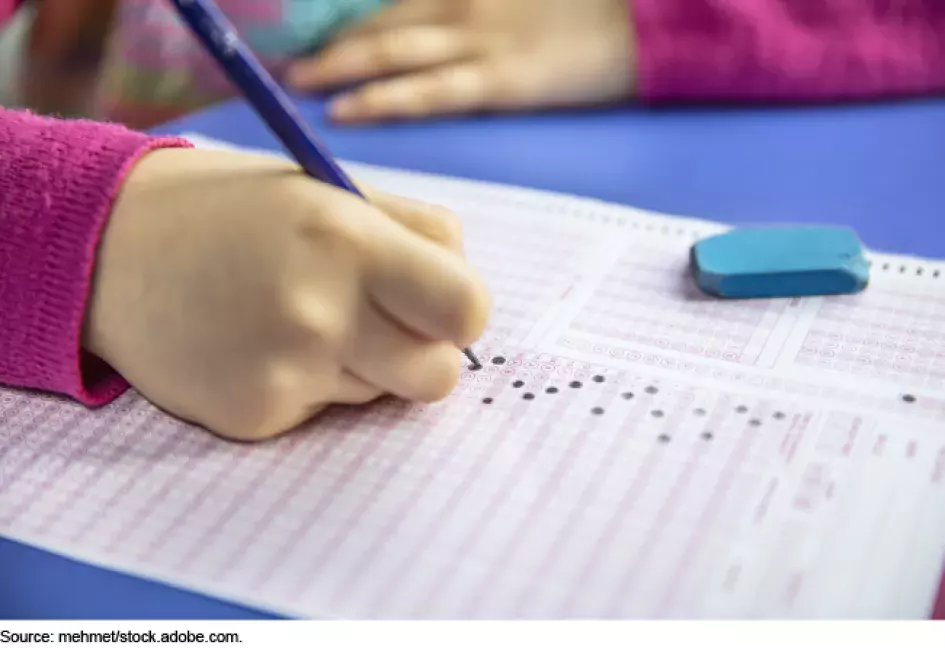 Photo close up showing a child filling in a bubble score card sheet for a standardized test