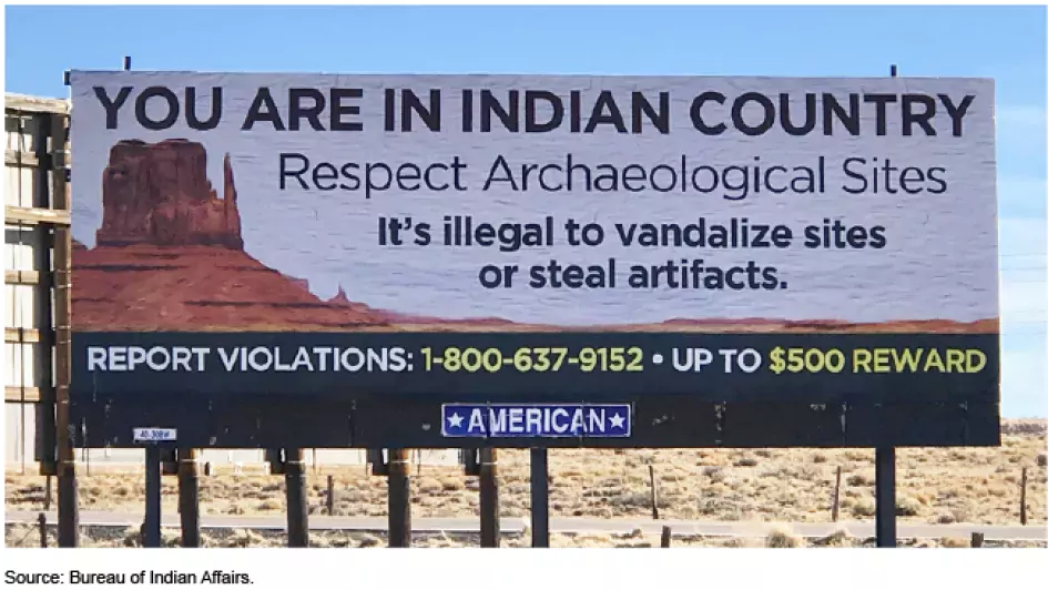 A billboard in a desert environment reads "You are in Indian Country. Respect Archaeological Sites. It's illegal to vandalize or steal artifacts. Report Violations, Up to $500 Reward.